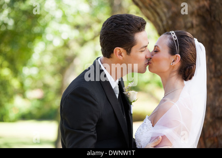 Romantic newlywed couple kissing in park Stock Photo