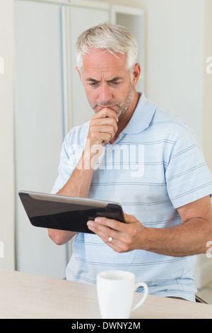 Thoughtful man using his tablet at breakfast Stock Photo
