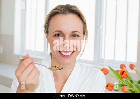 Smiling woman in bathrobe having cereal Stock Photo