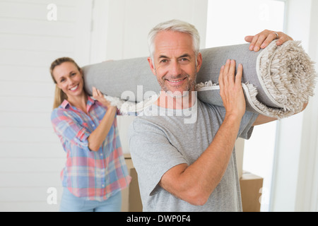 Happy couple carrying a rolled up rug together Stock Photo