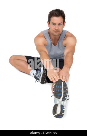 Portrait of a young man stretching hands to leg Stock Photo