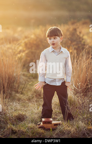 cute little boy with hands in the pockets on sunset in the field Stock Photo