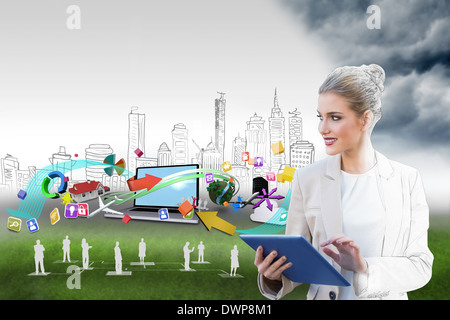 Blonde businesswoman using tablet pc with cityscape and laptop Stock Photo