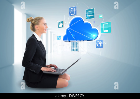 Blonde businesswoman sitting using laptop with cloud and app icons Stock Photo