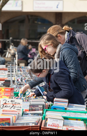 Girls rummaging through DVD's on market stall. Stock Photo