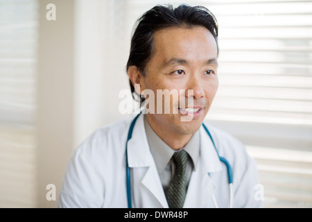 Thoughtful Doctor Smiling In Clinic Stock Photo