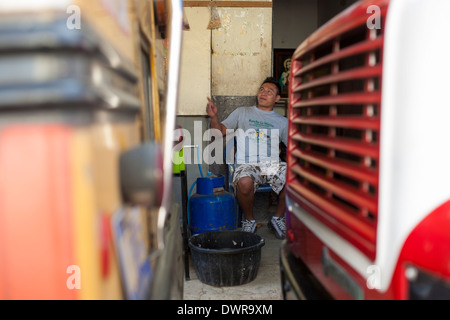 An attendent at the bus terminal laughs and jokes in the mountain town of Juayua on the rutas de la flores in El Salvador Stock Photo