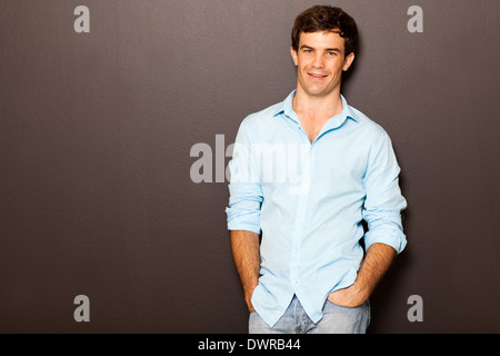 handsome man posing with hands in pockets on black Stock Photo