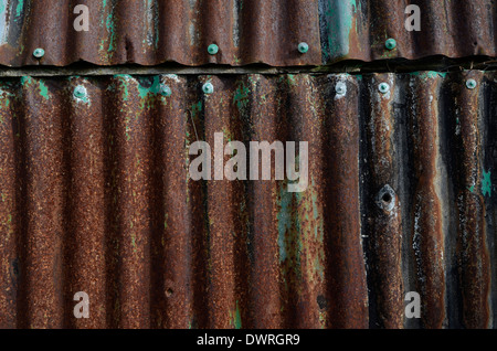 Abstract rusty metal texture of rippled steel sheet. Side wall of an abandoned shed. Stock Photo