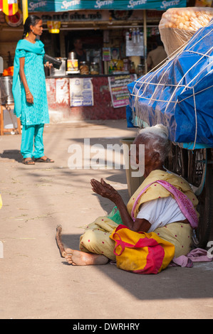 South Southern India Tamil Nadu Madurai street scene grey gray hair haired old lady woman female seated on road begs begging Stock Photo