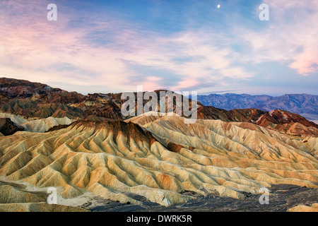 Civil twilight at dawn captures the moon over Golden Canyon Badlands in California’s Death Valley National Park. Stock Photo