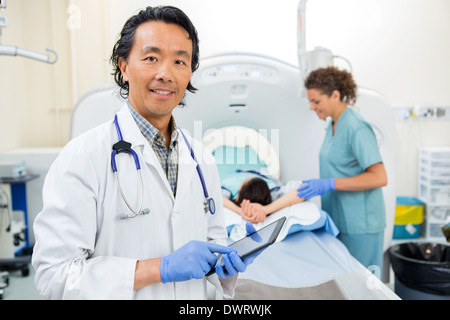 Radiologist Using Digital Tablet During CT Scan Stock Photo