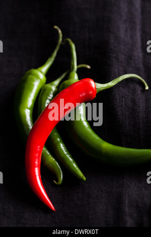 Closeup of four long red and green chili peppers on dark background Stock Photo