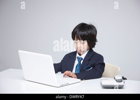 a kid wearing a business suit using a laptop Stock Photo