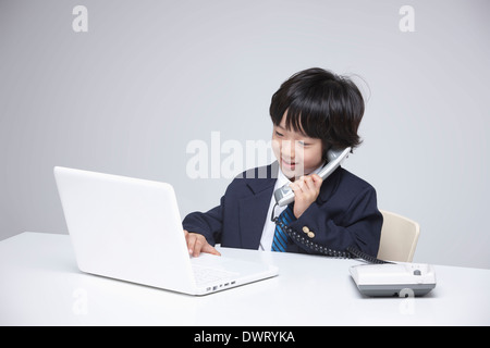 a kid wearing a business suit using a laptop Stock Photo