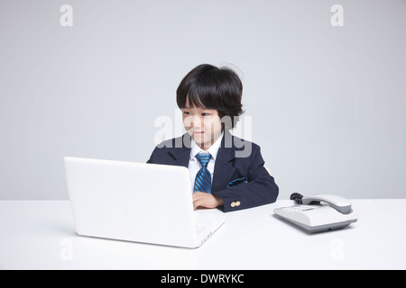 a kid wearing a business suit using a laptop Stock Photo