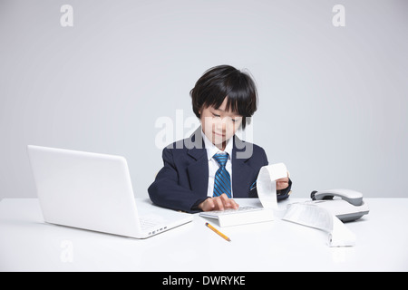 a kid wearing a business suit going through receipts Stock Photo