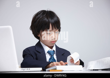 a kid wearing a business suit going through receipts Stock Photo