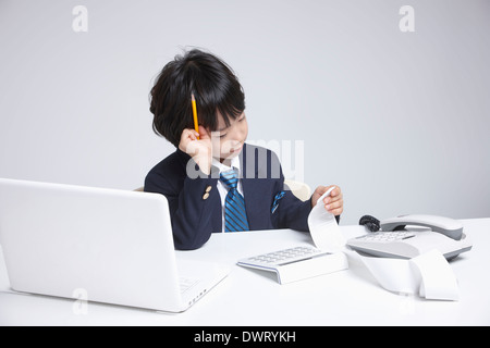 a kid wearing a business suit going through receipts Stock Photo