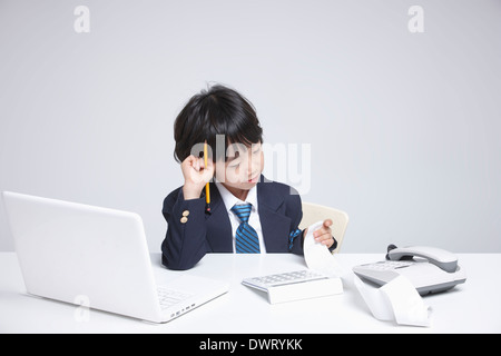 a kid wearing a business suit going through receipts Stock Photo