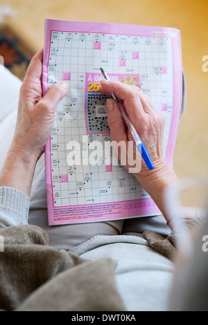 Elderly person doing cr-word puzzle Stock Photo