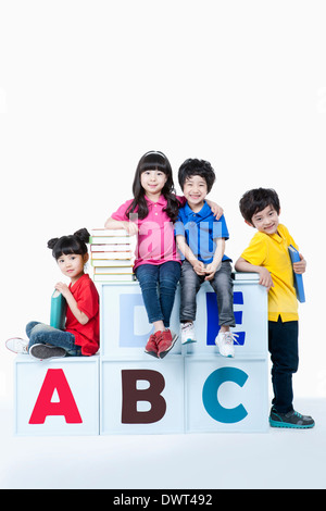 kids standing and sitting around alphabet blocks with books Stock Photo