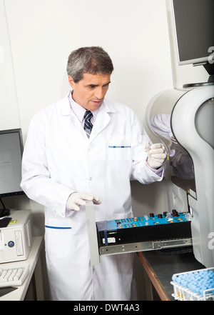 Scientist Loading Analyzer With Samples Stock Photo