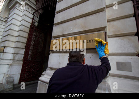 Westminster London, UK.13th March 2014. A worker polishes the brass plaque at the Foreign and Commonwealth Office in London Stock Photo
