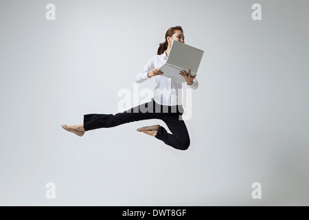 a woman making dance poses with a laptop Stock Photo