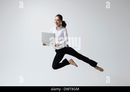 a woman making dance poses with a laptop Stock Photo