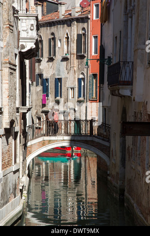 A couple stroll over a picturesque bridge amongst the back canals of Venice, Italy. Stock Photo