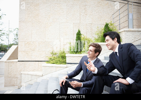 two business men sitting outside on the stairs Stock Photo