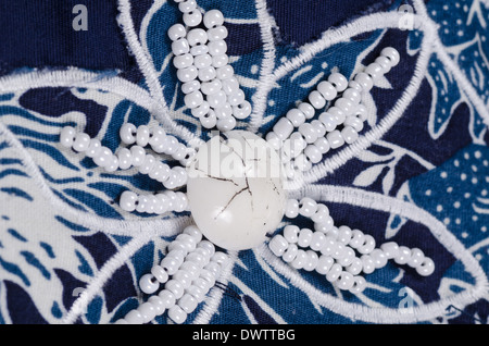 Embroidered flower shaped bead pattern on blue fabric Stock Photo