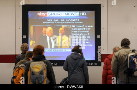 Munich, Germany. 13th Mar, 2014. People watch an infomation sign with the report of the verdict in the tax evasion trial against President of FC Bayern Munich Uli Hoeness in a metro station in Munich, Germany, 13 March 2014. Hoeness was sentenced to three and a half years for tax evasion. Photo: Tobias Hase/dpa/Alamy Live News Stock Photo