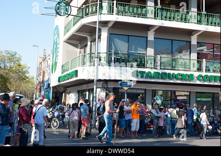 Crowds line the streets outside Starbucks Coffee shop in Chiang Mai waiting for the annual Flower Festival Parade to start. Stock Photo