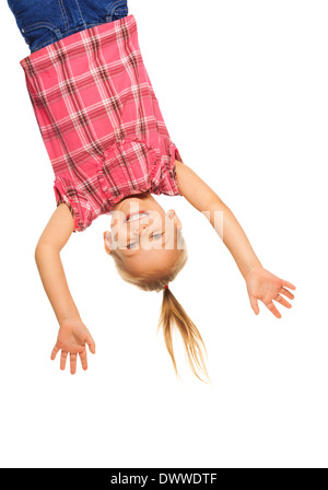 Happy laughing 4 years old girl hanging upside down isolated on white with smile on her face Stock Photo