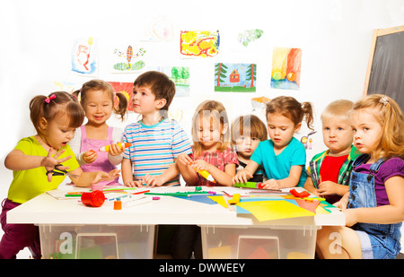 Large group of little kids painting with pencils and gluing with glue stick on art class in kindergarten Stock Photo