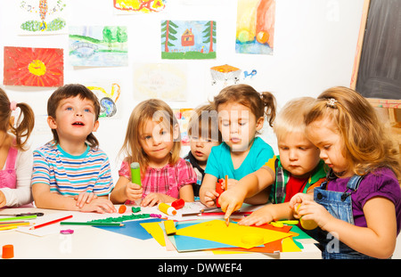 Group of little kids painting with pencils and gluing with glue stick on art class in kindergarten Stock Photo