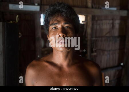 Mar 2, 2014 - Ko Surin, Thailand - Nguy, a Moken man, in his house in Ko Surin National Park. Often called sea nomads or sea gypsies, the Moken are a seafaring people who for centuries lived nomadically on the Andaman Sea. However, due to stricter border control, commercial overfishing, rapid development, and tourism, the Moken have gradually been forced to adopt a settled lifestyle. Today, the Moken who live in Koh Surin National Park, one of Thailand's most remote group of islands, have it better than many of their kin and are still able to live a lifestyle largely based on tradition and the Stock Photo
