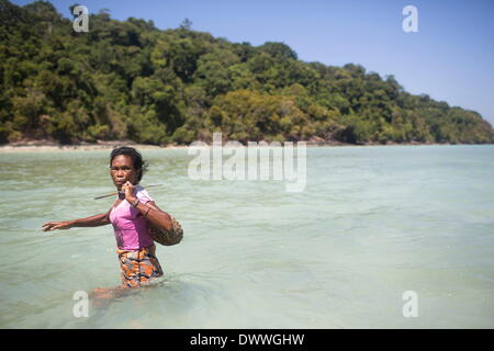 Mar 1, 2014 - Ko Surin, Thailand - A Moken woman wades through shallow water towards a beach to forage. Often called sea nomads or sea gypsies, the Moken are a seafaring people who for centuries lived nomadically on the Andaman Sea. However, due to stricter border control, commercial overfishing, rapid development, and tourism, the Moken have gradually been forced to adopt a settled lifestyle. Today, the Moken who live in Koh Surin National Park, one of Thailand's most remote group of islands, have it better than many of their kin and are still able to live a lifestyle largely based on traditi Stock Photo