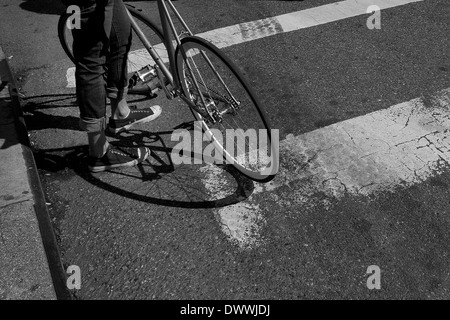 View of a cyclist's legs with bicycle resting against his leg, New York, USA Stock Photo
