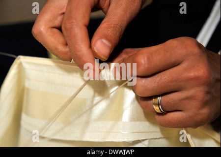 Close-up details of traditional hand stitching the edging seam on summer light weight kaftan robe, Marrakech, Morocco Stock Photo