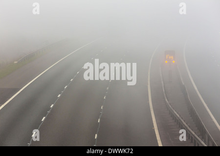 UK motorway with fog warning sign in fog or foggy conditions Stock Photo