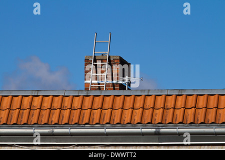 Ladder is leaning on a chimney of a multi storied house Stock Photo