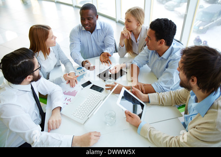 Group of business partners listening to one of colleagues at meeting