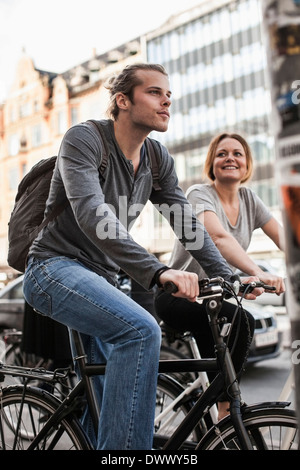 Man and woman cycling on city street Stock Photo