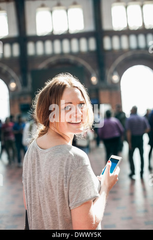 Portrait of happy woman with mobile phone standing at railway station Stock Photo