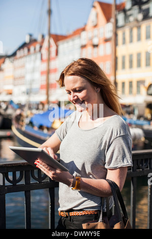 Smiling woman using digital tablet by railing at harbor Stock Photo