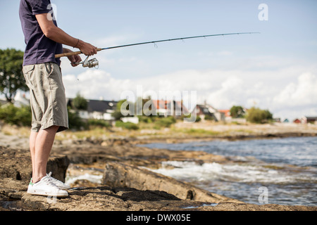 Low section of mature man fishing at lakeshore Stock Photo