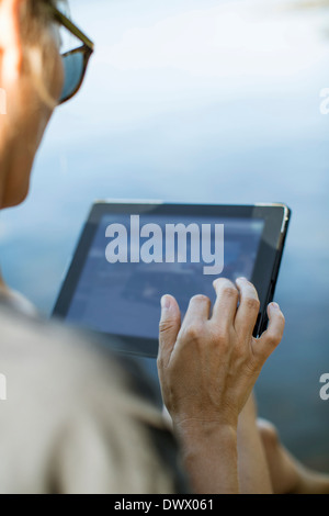 Cropped image of mid adult woman using digital tablet outdoors Stock Photo